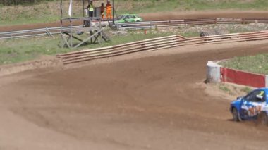 Çakıl taşı pistinde araba yarışı, yarışmaya katılarak birincilik için mücadele. Taşlar arabanın lastiklerinden uçuyor. Arabalar katılıyor. Brenguli.