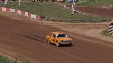 Çakıl taşı pistinde araba yarışı, yarışmaya katılarak birincilik için mücadele. Taşlar arabanın lastiklerinden uçuyor. Arabalar katılıyor