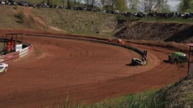 Çakıl taşı pistinde araba yarışı, yarışmaya katılarak birincilik için mücadele. Taşlar arabanın lastiklerinden uçuyor. Arabalar katılıyor