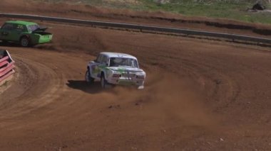 Çakıl taşı pistinde araba yarışı, yarışmaya katılarak birincilik için mücadele. Taşlar arabanın lastiklerinden uçuyor. Arabalar katılıyor