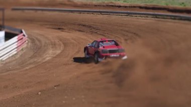 Çakıl taşı pistinde araba yarışı, yarışmaya katılarak birincilik için mücadele. Taşlar arabanın lastiklerinden uçuyor. Arabalar katılıyor