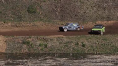 Çakıl taşı pistinde araba yarışı, yarışmaya katılarak birincilik için mücadele. Taşlar arabanın lastiklerinden uçuyor. Arabalar katılıyor