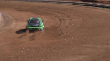 Çakıl taşı pistinde araba yarışı, yarışmaya katılarak birincilik için mücadele. Taşlar arabanın lastiklerinden uçuyor. Arabalar katılıyor
