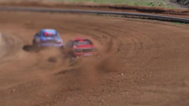 Çakıl taşı pistinde araba yarışı, yarışmaya katılarak birincilik için mücadele. Taşlar arabanın lastiklerinden uçuyor. Arabalar katılıyor