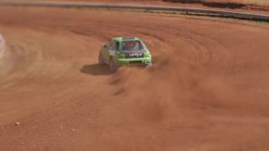 Çakıl taşı pistinde araba yarışı, yarışmaya katılarak birincilik için mücadele. Taşlar arabanın lastiklerinden uçuyor. Arabalar katılıyor