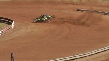 Çakıl taşı pistinde araba yarışı, yarışmaya katılarak birincilik için mücadele. Taşlar arabanın lastiklerinden uçuyor. Arabalar katılıyor