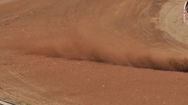 Çakıl taşı pistinde araba yarışı, yarışmaya katılarak birincilik için mücadele. Taşlar arabanın lastiklerinden uçuyor. Arabalar katılıyor