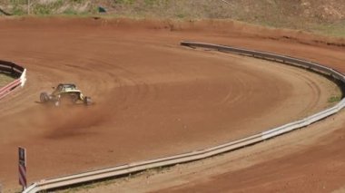 Çakıl taşı pistinde araba yarışı, yarışmaya katılarak birincilik için mücadele. Taşlar arabanın lastiklerinden uçuyor. Arabalar katılıyor