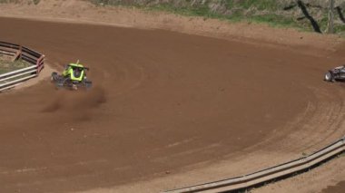 Çakıl taşı pistinde araba yarışı, yarışmaya katılarak birincilik için mücadele. Taşlar arabanın lastiklerinden uçuyor. Arabalar katılıyor