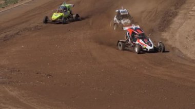 Çakıl taşı pistinde araba yarışı, yarışmaya katılarak birincilik için mücadele. Taşlar arabanın lastiklerinden uçuyor. Arabalar katılıyor