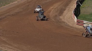 Çakıl taşı pistinde araba yarışı, yarışmaya katılarak birincilik için mücadele. Taşlar arabanın lastiklerinden uçuyor. Arabalar katılıyor