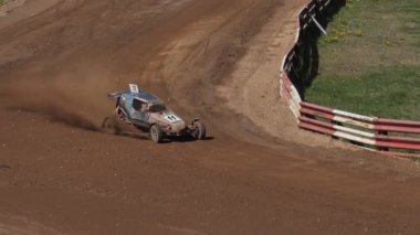 Çakıl taşı pistinde araba yarışı, yarışmaya katılarak birincilik için mücadele. Taşlar arabanın lastiklerinden uçuyor. Arabalar katılıyor