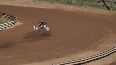 Çakıl taşı pistinde araba yarışı, yarışmaya katılarak birincilik için mücadele. Taşlar arabanın lastiklerinden uçuyor. Arabalar katılıyor