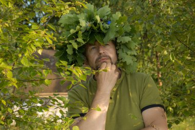 Başında meşe yaprağı çelengi var. Kafasında taç olan bir adam. Yeşiller 'de yaz dönümünü kutluyoruz. Bir meşe çelengiyle yaz ortası kutlaması