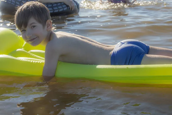 Boy is sleeping on an inflatable mattress in the water. The child alone in the water. A young man smiles while sleeping in the water. Soft selective focus