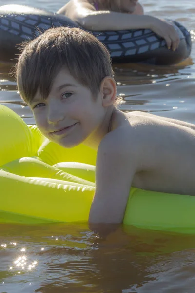 Boy is sleeping on an inflatable mattress in the water. The child alone in the water. A young man smiles while sleeping in the water. Soft selective focus