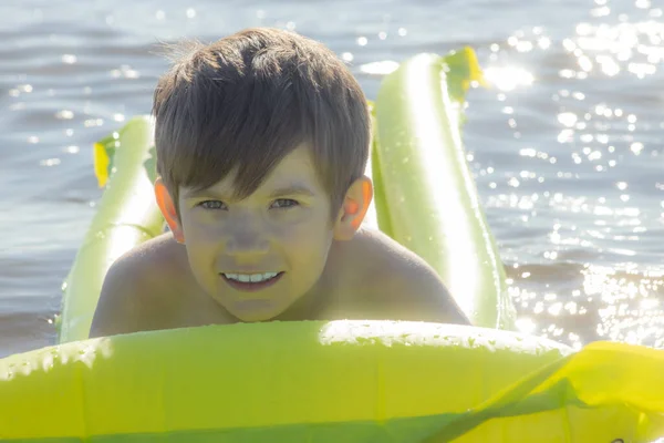 Boy is sleeping on an inflatable mattress in the water. The child alone in the water. A young man smiles while sleeping in the water. Soft selective focus