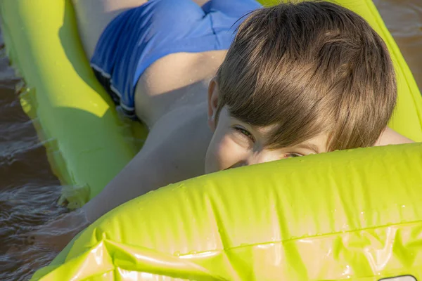 Boy is sleeping on an inflatable mattress in the water. The child alone in the water. A young man smiles while sleeping in the water. Soft selective focus