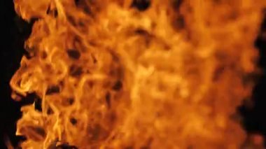 Siyah arka planda yangın alevi. Ateş alevi karanlıkta dans eder. Yumuşak sinema filmi. Ekranda güçlü alevler var. Yumuşak seçici odak.