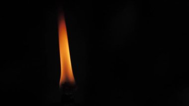 Siyah bir arkaplanda meşaleden çıkan alev. Ateş alevi karanlıkta dans eder. Yumuşak sinema filmi. Ekranda uçuşan güçlü bir alev. Yumuşak seçici odak.
