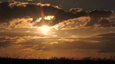 Gökyüzünde altın gün batımı. Bulutların üzerindeki güneş ışığının yansıması. Güzel, sarı bir akşam fotoğrafı. Bulutların arkasına güneş batıyor. Muhteşem gün batımı manzarası. İnanılmaz doğa ışığı bulutlu gökyüzü.