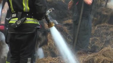 Fireman extinguish fire with the hose. Firefighters put out a burning grain forge.The grain dryer burned down. 