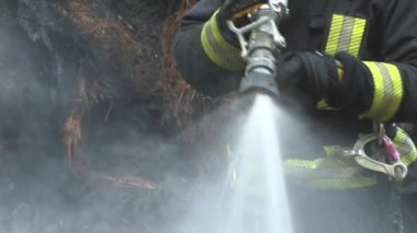 Fireman extinguish fire with the hose. Firefighters put out a burning grain forge.The grain dryer burned down. 