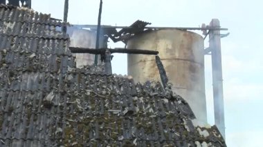 Firemen put out a burning grain mill. A fireman puts out the fire with a hose. The grain dryer burned down.