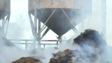 Firemen put out a burning grain mill. A fireman puts out the fire with a hose. The grain dryer burned down.