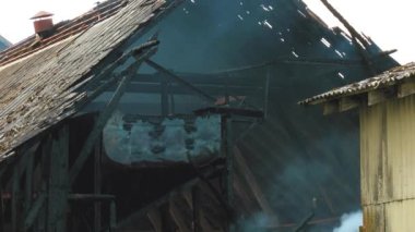 Firemen put out a burning grain mill. A fireman puts out the fire with a hose. The grain dryer burned down.