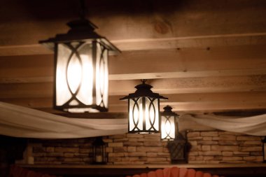 Outdoor lanterns on the wooden ceiling. Bright lanterns on the ceiling of a wooden house