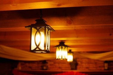 Outdoor lanterns on the wooden ceiling. Bright lanterns on the ceiling of a wooden house