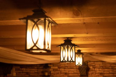 Outdoor lanterns on the wooden ceiling. Bright lanterns on the ceiling of a wooden house