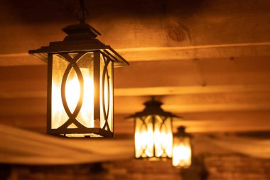 Outdoor lanterns on the wooden ceiling. Bright lanterns on the ceiling of a wooden house