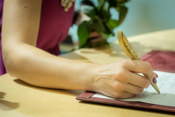 A person signs a document. Pen with paper