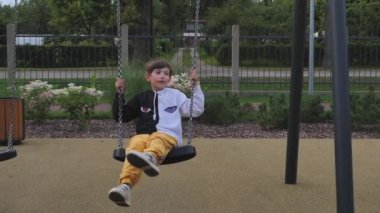 A little boy was swinging on a swing. Playground with one child. The boy rested on the swing