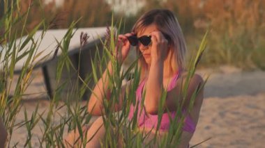 Woman in swimsuit at sunset by the sea. A young girl was sunbathing on the shore of the beach.