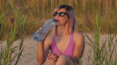 Woman in swimsuit at sunset by the sea. A young girl was sunbathing on the shore of the beach.