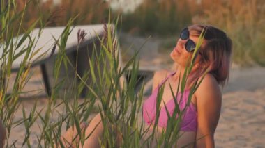 Woman in swimsuit at sunset by the sea. A young girl was sunbathing on the shore of the beach.