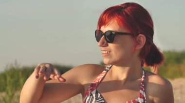 Woman in swimsuit at sunset by the sea. A young girl was sunbathing on the shore of the beach.