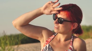 Woman in swimsuit at sunset by the sea. A young girl was sunbathing on the shore of the beach.