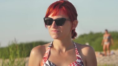 Woman in swimsuit at sunset by the sea. A young girl was sunbathing on the shore of the beach.