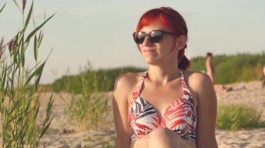 Woman in swimsuit at sunset by the sea. A young girl was sunbathing on the shore of the beach.