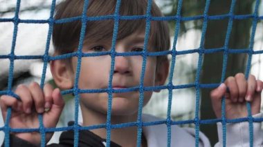 Çocuk ellerini ağda tutuyor. Çocuk ağda oynuyordu. Bir çocukla oyun parkı