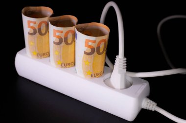Elektrik tüketicileri için pahalı. Avro banknotlarının elektrik prizleri siyah arka planda. Pahalı elektrik maliyeti kavramı ve enerji faturası fiyatlarındaki artış.