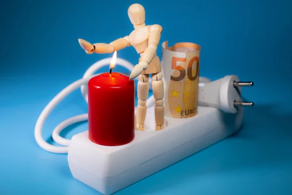 Energy price increase. Burning candles with a wooden man warming himself by the candle. Increase in energy bill prices.