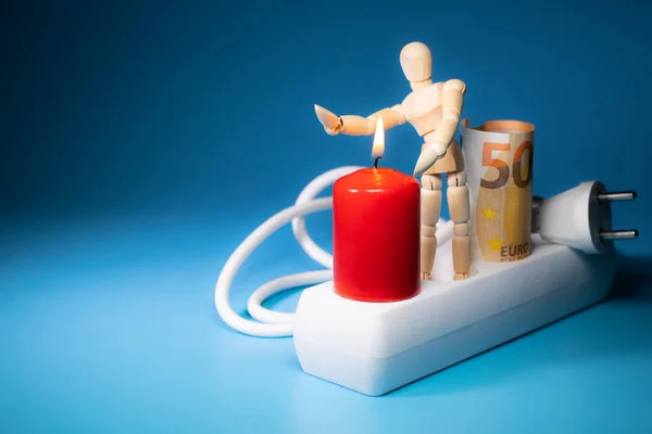 Energy price increase. Burning candles with a wooden man warming himself by the candle. Increase in energy bill prices.