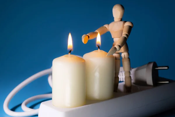 Energy price increase. Burning candles with a wooden man warming himself by the candle. Increase in energy bill prices.