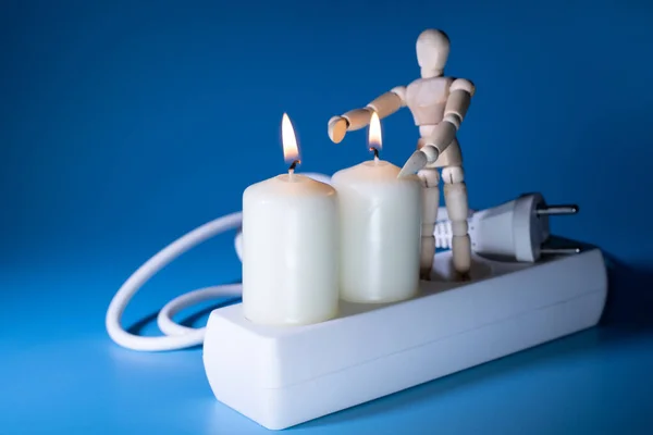 Energy price increase. Burning candles with a wooden man warming himself by the candle. Increase in energy bill prices.