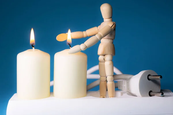 Energy price increase. Burning candles with a wooden man warming himself by the candle. Increase in energy bill prices.